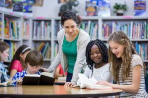 Elementary students working with teacher in library